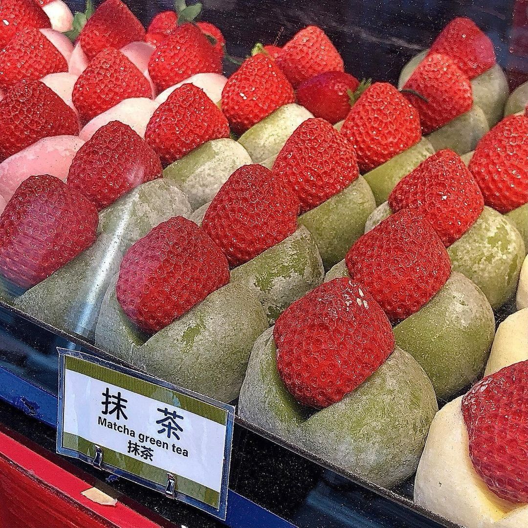Close-up of strawberry daifuku mochi, including green matcha daifuku topped with strawberries