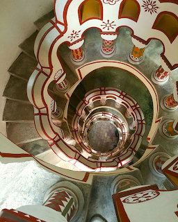 Aerial view of ornate spiral staircase with decorative railings in cream, red and green colors