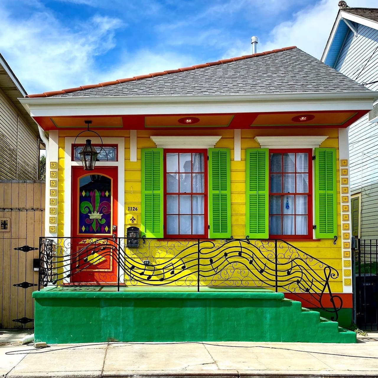 Yellow house exterior painted with musical notes and colorful shutters