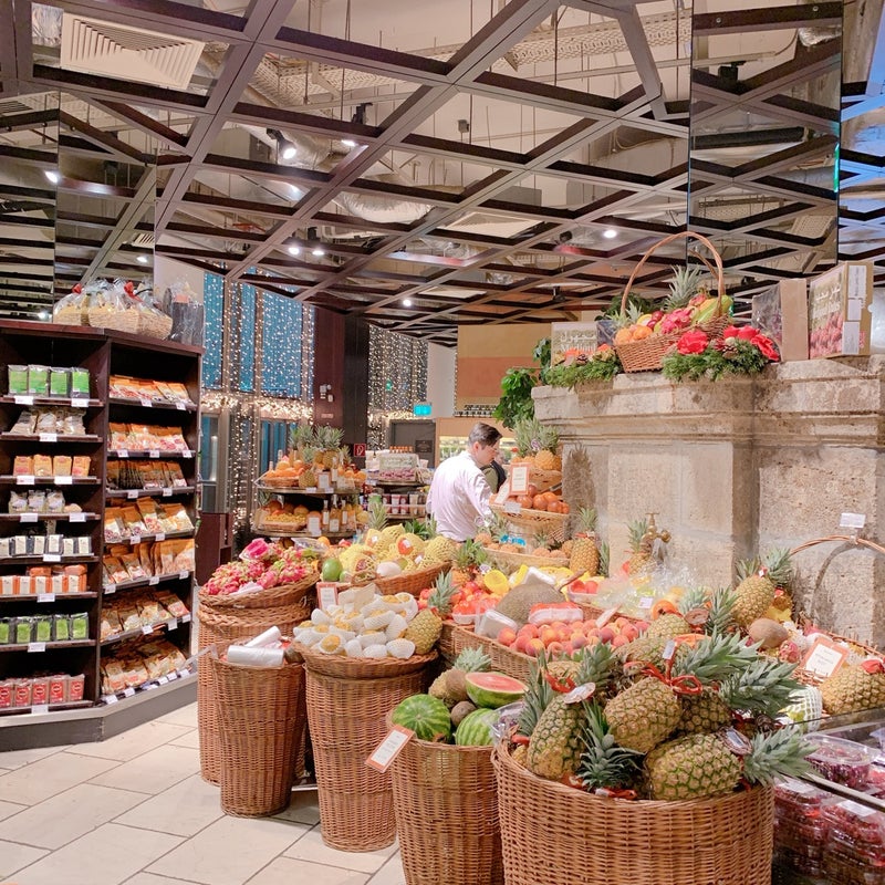 Indoor European market with produce baskets, flowers, and stocked shelves under wooden beams
