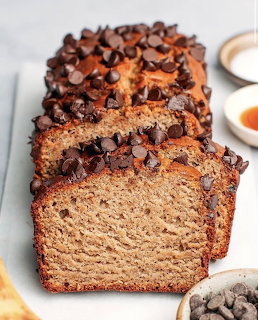 Sliced chocolate chip banana bread loaf on white board with two slices cut, showing soft interior crumb