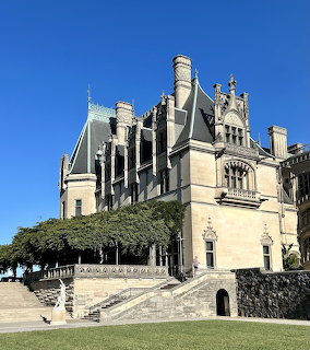 Biltmore Estate mansion with Gothic architecture, stone walls, and green lawn against blue sky