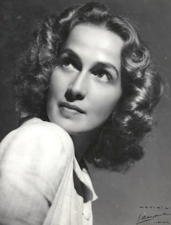 Black and white portrait of a woman with curled hair wearing a white blouse in1940s style