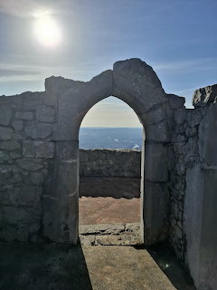 Stone arch ruins with sunlight and blue sky framing a landscape view