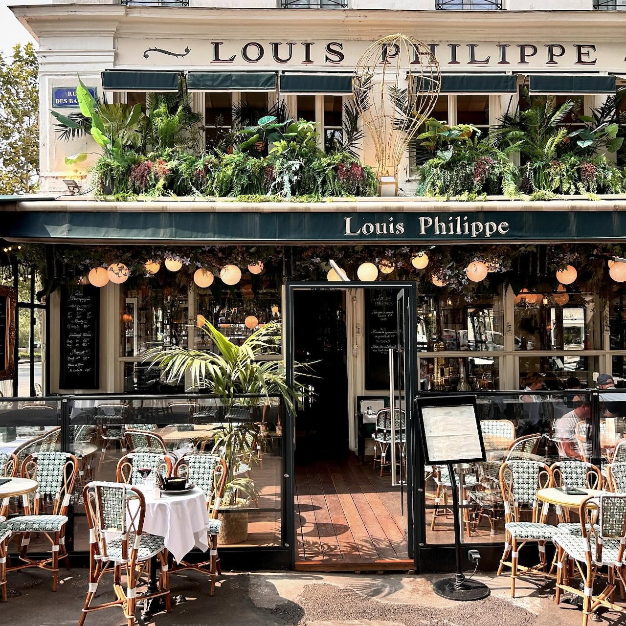 Traditional Parisian cafe storefront with bistro seating and green awning
