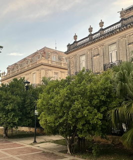 Ornate colonial twin buildings in Mérida with green trees and garden in foreground