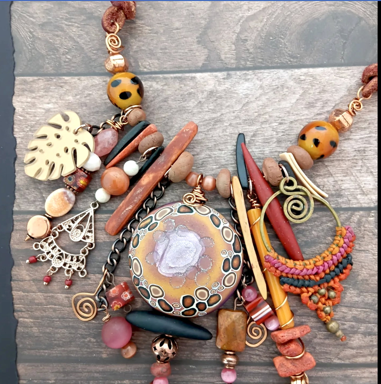Assorted jewelry beads, pendants, cords, and charms arranged on a wooden background