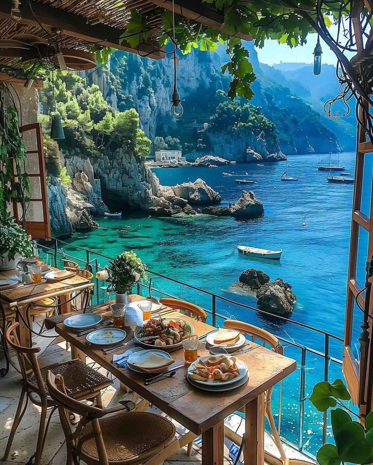 Dining table on coastal terrace with turquoise water and cliffs view