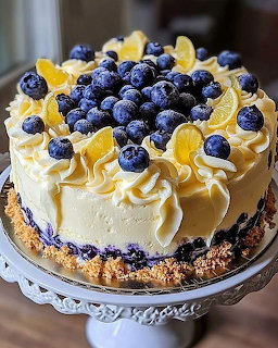 Blueberry cake with white frosting, fresh blueberries, and lemon slices on a cake stand