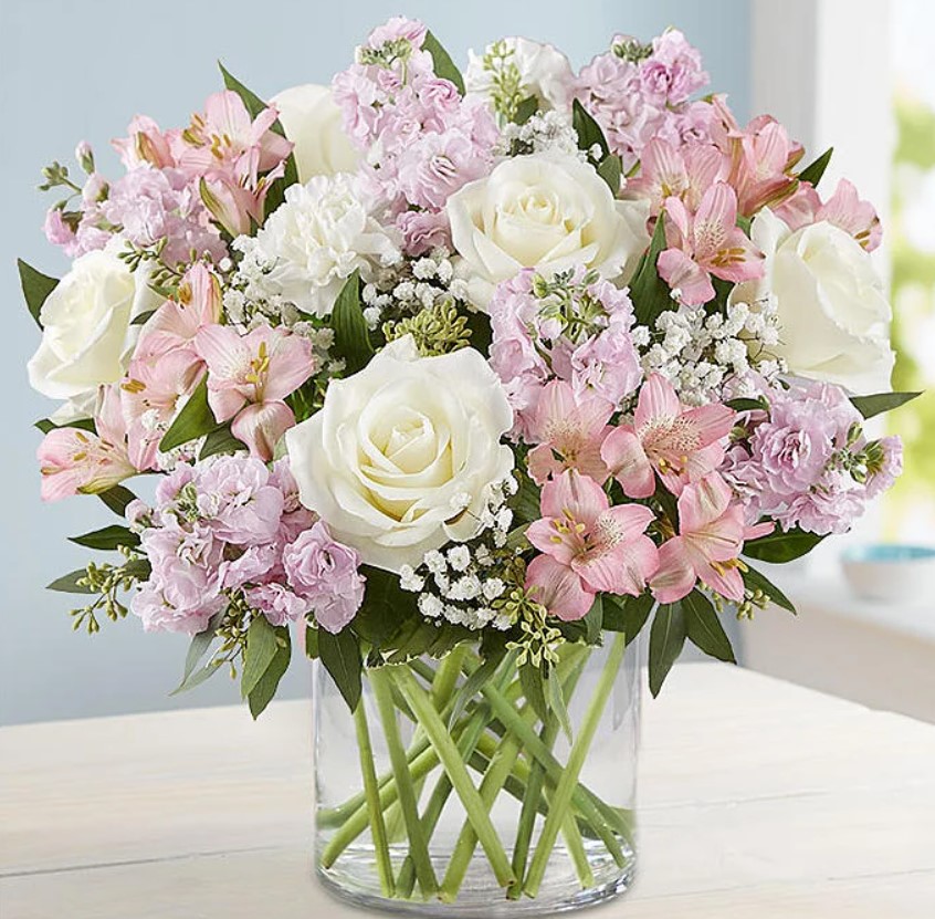 Pink and white flower bouquet in glass vase on white surface
