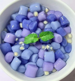 Bowl of blue and purple jelly cubes with white pearls and mint leaves