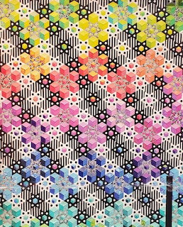 Colorful patchwork quilt with repeating star pattern on striped polka dot background