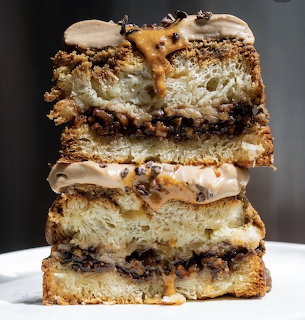 Two stacked slices of layered cream cake with chocolate bits on a white plate