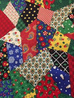 Colorful patchwork quilt with diverse fabric patterns including florals, stars, and geometric shapes