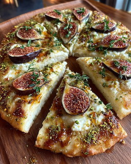 Flatbread pizza topped with sliced figs, cheese, herbs, and crushed pistachios on a wooden board
