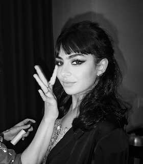 Black-and-white portrait of Charli XCX posing with her hand beside her face