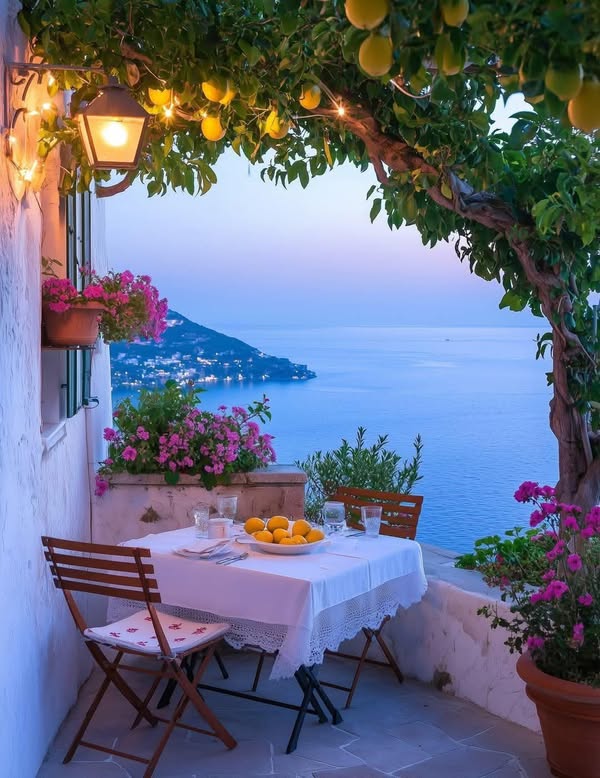 Lakeside patio with table, chairs, flowers, and vine arch overlooking blue water