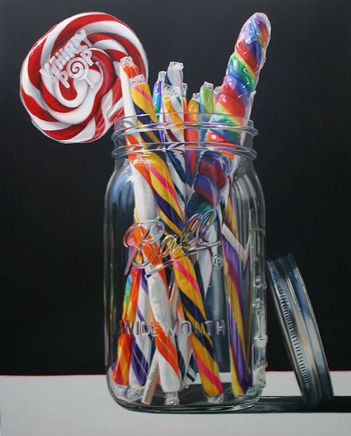 Glass jar with colorful striped candy sticks and red swirl lollipop on dark background