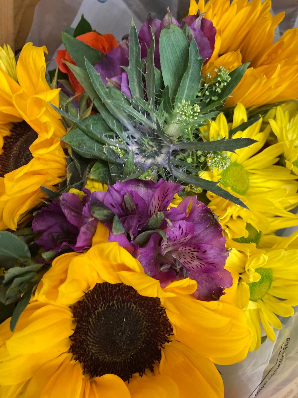 Close-up of a flower bouquet with yellow sunflowers, purple alstroemeria, and green leaves