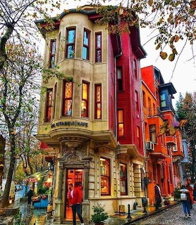 Ornate corner cafe building on a wet Istanbul street with autumn trees and colorful facades