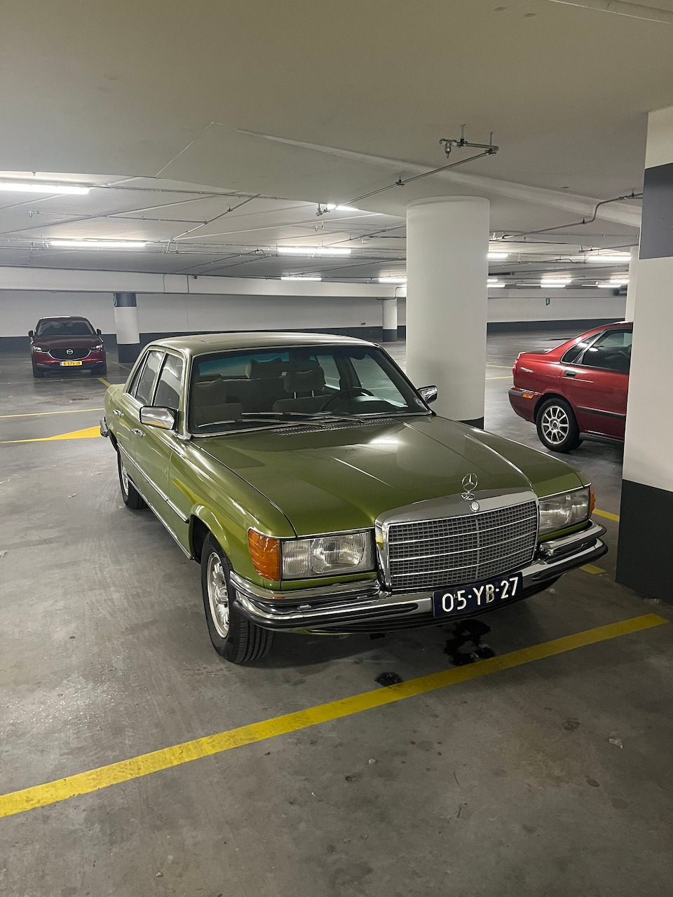 Classic olive green Mercedes-Benz 280S parked in an underground parking garage