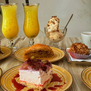 Assorted desserts including cake, pastries, and ice cream with yellow drinks on striped plates