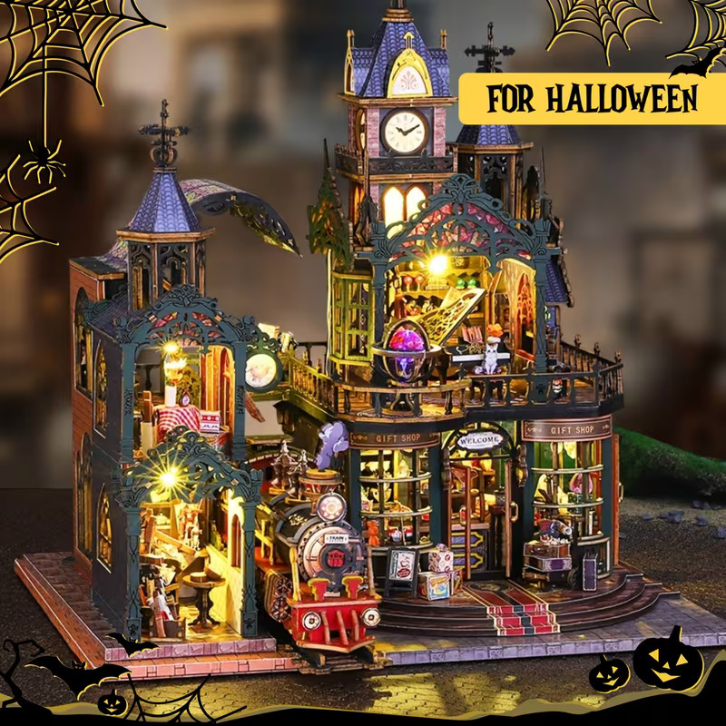 Halloween miniature house with lit windows, clock tower, spider webs, and a small red train
