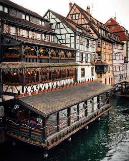 Half-timbered buildings beside a narrow canal with a covered dock on the water