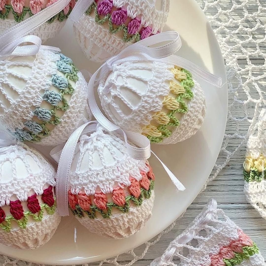 Pastel crocheted egg ornaments in a white bowl on a lace tablecloth