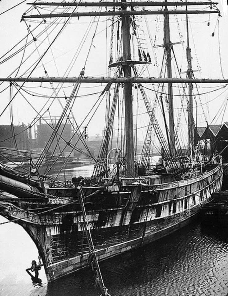 Black-and-white view of the tall ship Cutty Sark moored at a dock with masts and rigging