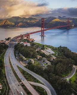 Golden Gate Bridge at sunset with highway and bay waters, aerial perspective