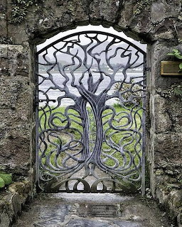 Ornate metal gate with tree pattern in stone archway