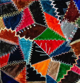 Colorful patchwork quilt with triangular fabric patches and white decorative stitching