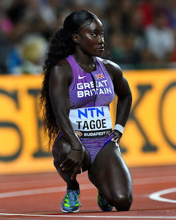 Female track athlete kneeling on a running track in a purple Great Britain uniform