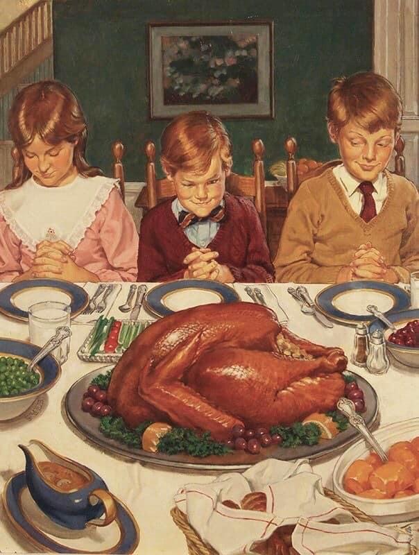 Three children seated at Thanksgiving dinner table, heads bowed in prayer before roasted turkey and festive meal