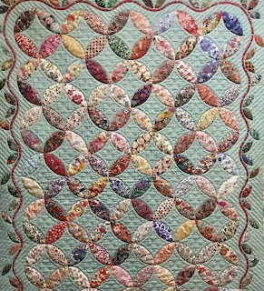 Patchwork quilt with curved interlocking pieces in floral fabrics and scalloped edges