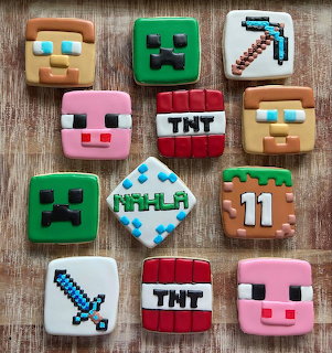 Grid of 12 square frosted cookies decorated with Minecraft character faces and game items on wooden surface