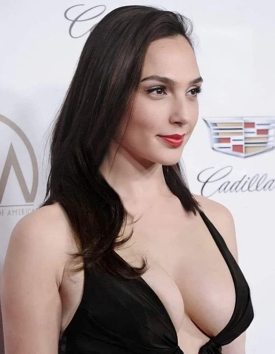 Woman with long dark hair wearing a low-cut black dress and red lipstick at a formal event