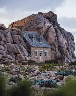Old stone house built into large rocky boulders on mountainside