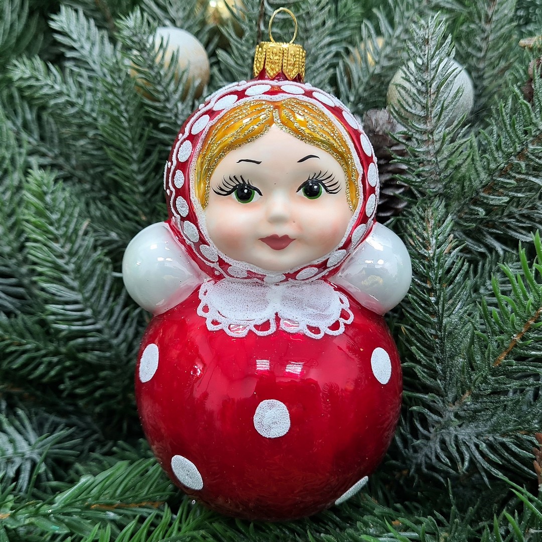 Red matryoshka-style Christmas ornament hanging in green fir branches