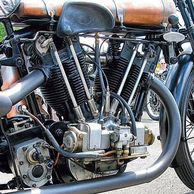 Close-up of a vintage motorcycle engine with exposed cylinders and curved exhaust pipes