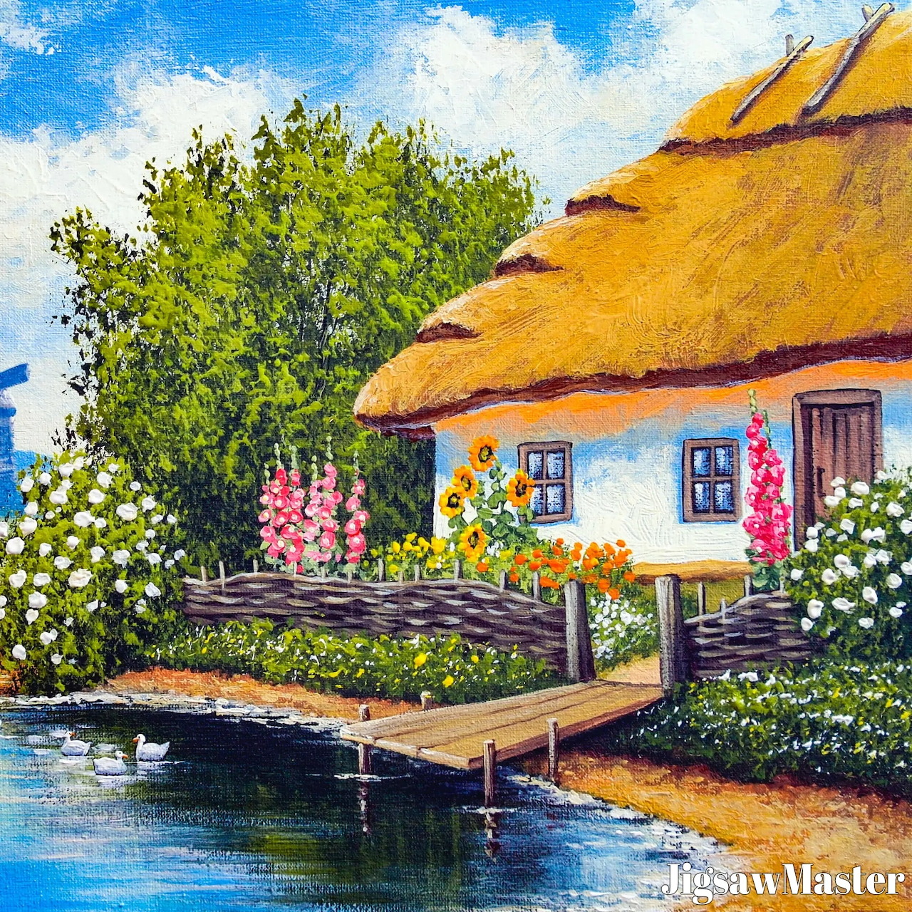 White cottage with thatched roof next to water with wooden dock, garden flowers and blue sky
