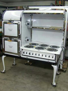Antique white electric stove with chrome trim, multiple coil burners, and decorative cabinet doors on elegant legs