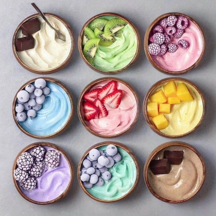 Nine colorful smoothie bowls in a grid with fruit and chocolate toppings