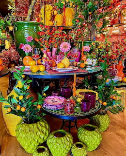 Colorful tropical table display with fruits, flowers, green vases, purple plates and vibrant decorations