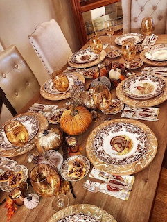Thanksgiving table with turkey, pumpkins, decorated plates, candles, and autumn centerpieces