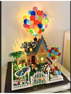 Lego model of the Up movie house with colorful lit balloons, garden, and white picket fence