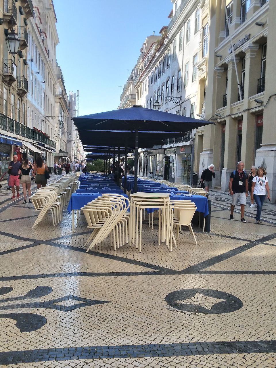 Lisbon pedestrian street with decorative pavement, café kiosk, and white buildings