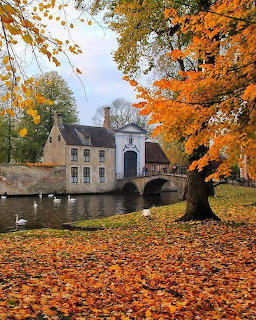 Stone house by canal with autumn trees and bridge