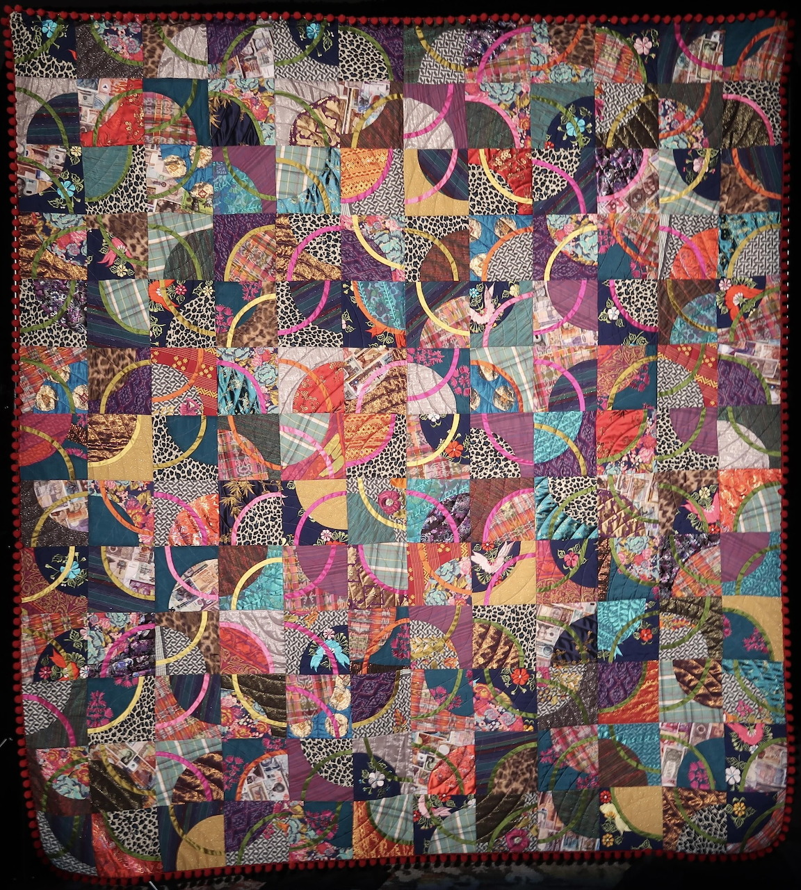 Detailed vintage patchwork quilt with geometric shapes and floral fabric patterns in warm and cool tones